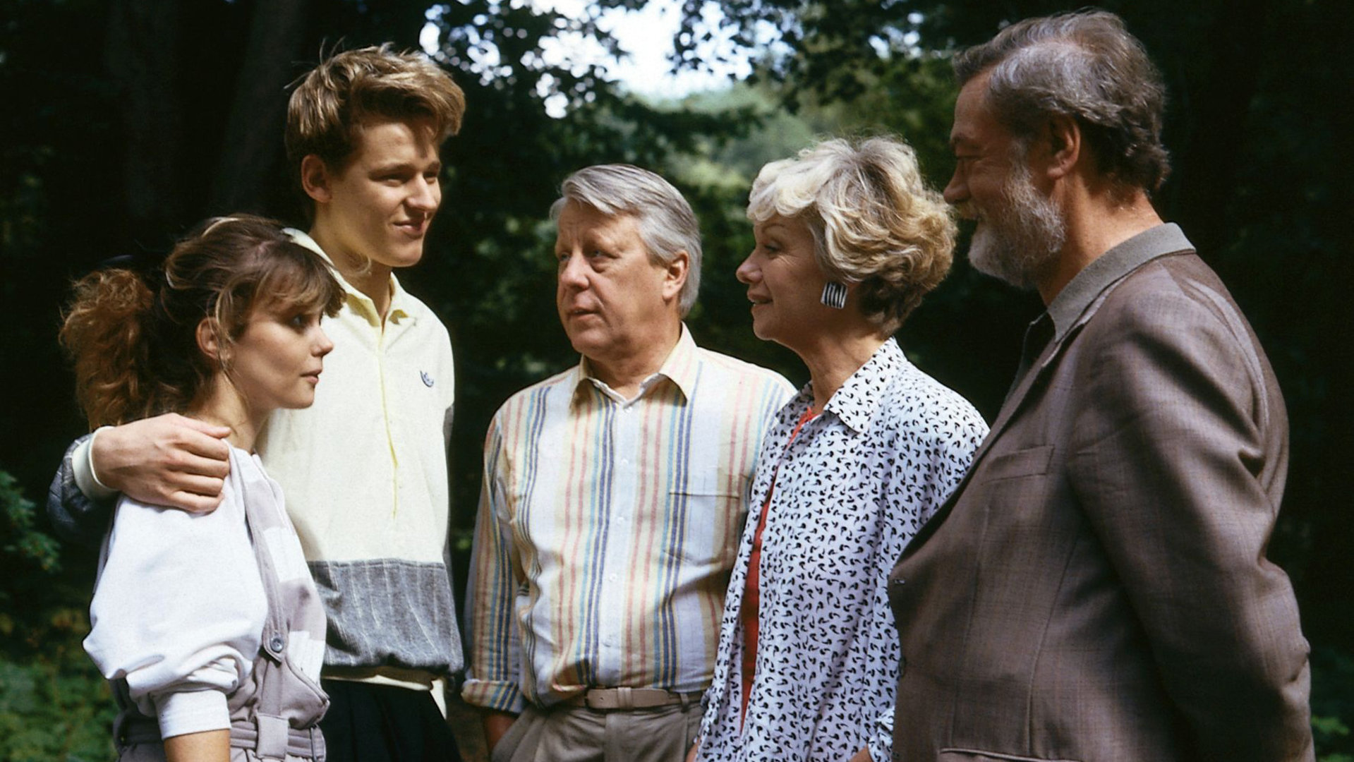"Die Wicherts von nebenan: Der Unfall": In einem Wald. Hannelore (Maria Sebaldt), Eberhard (Stephan Orlac) und Graf Hasso (Friedrich Schütter) stehen neben Andy (Hendrik Martz) und Gaby (Roswitha Schreiner) und blicken das junge Paar fröhlich an.