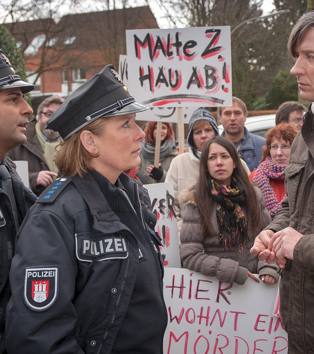 Bäckermeister Mittelbach (Martin Armknecht, r.) ist das Sprachrohr eines aufgewühlten Mobs gegen die Unterbringung des Gewaltstraftäters Zühl in ihrer Nachbarschaft. Claudia (Janette Rauch) und Tarik (Serhat Cokgezen, l.) versuchen zu beruhigen. 
(Rest: Komparsen)