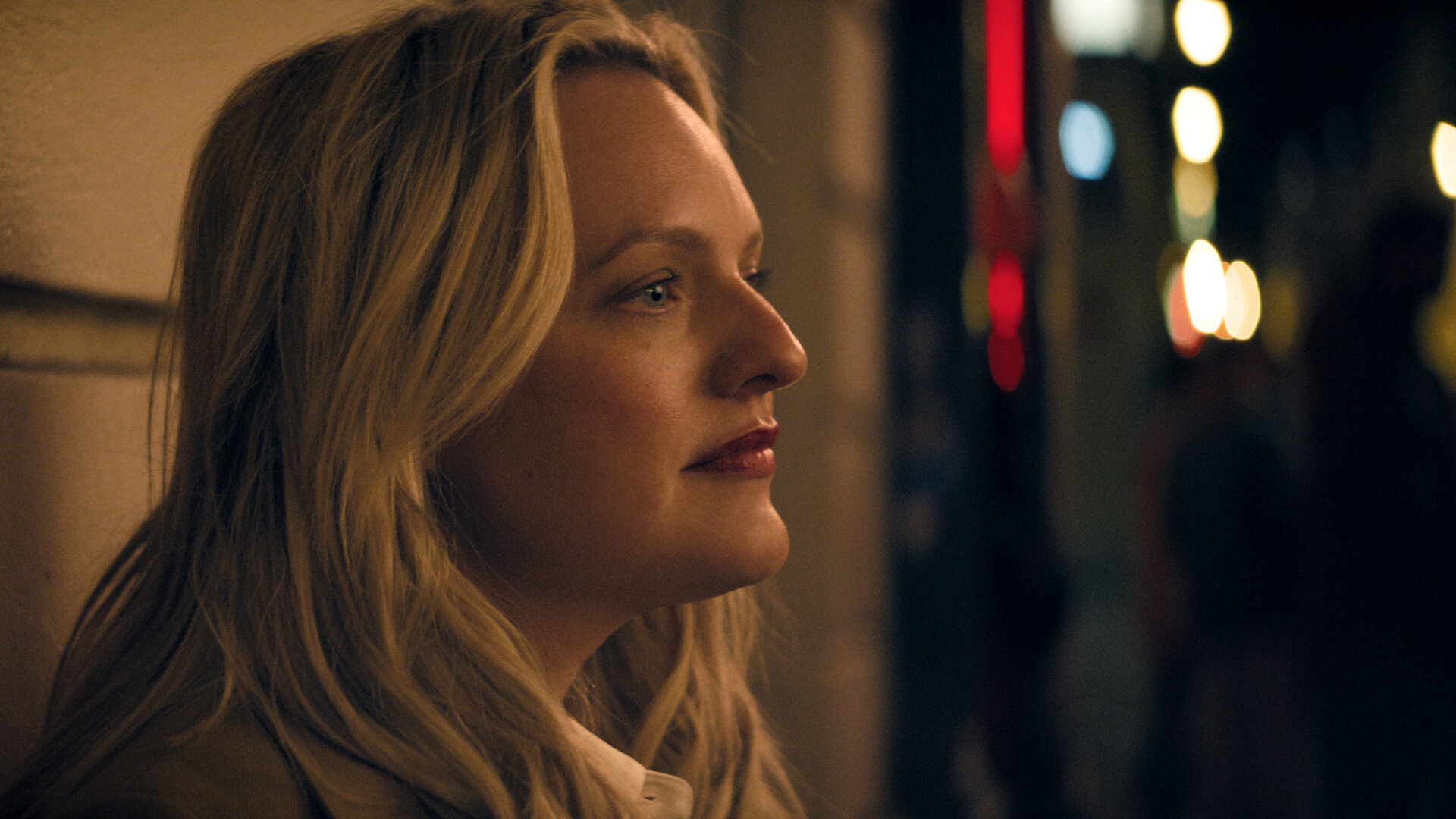 "The Veil - Kein Zurück": Imogen Salter (Elisabeth Moss) steht im Dunkeln vor einer Hauswand. Im Hintergrund sind verschwommene Lichter zu sehen.