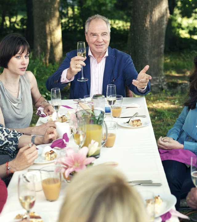 "Familie Sonntag auf Abwegen": Moni Sonntag (Anna Maria Sturm), Sylvie (Sissy Höferer), Karo Sonntag (Christiane Paul), Franz Sonntag (Friedrich von Thun), Lorena (Carolina Vera), Robert Sonntag (Sebastian Bezzel) und Bärbel Sonntag (Gisela Schneeberger) sitzen im Wald um einen Tisch herum und halten Sektgläser in den Händen.