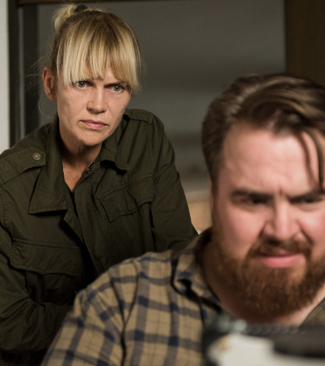 "Helen Dorn - Atemlos": Weyer (Tristan Seith) sitzt an einem Tisch und schaut konzentriert vor sich. Helen Dorn (Anna Loos) steht hinter ihm und schaut in die gleiche Richtung.