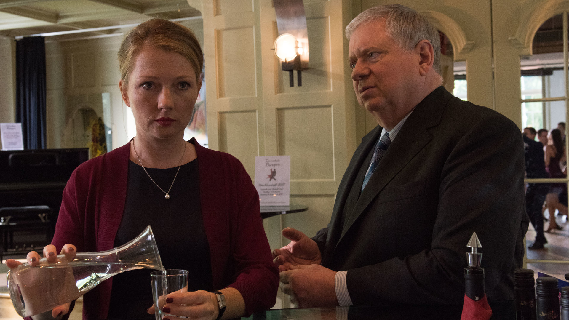 "Der Staatsanwalt – Im Netz der Spinne": Sybille Wunderlich (Katja Studt) und Bernd Reuther (Rainer Hunold) stehen nebeneinander an einer Bar. Sie schaut apathisch nach vorne, während Reuther sie anschaut.