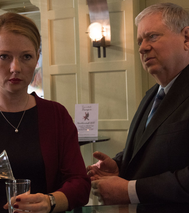 "Der Staatsanwalt – Im Netz der Spinne": Sybille Wunderlich (Katja Studt) und Bernd Reuther (Rainer Hunold) stehen nebeneinander an einer Bar. Sie schaut apathisch nach vorne, während Reuther sie anschaut.