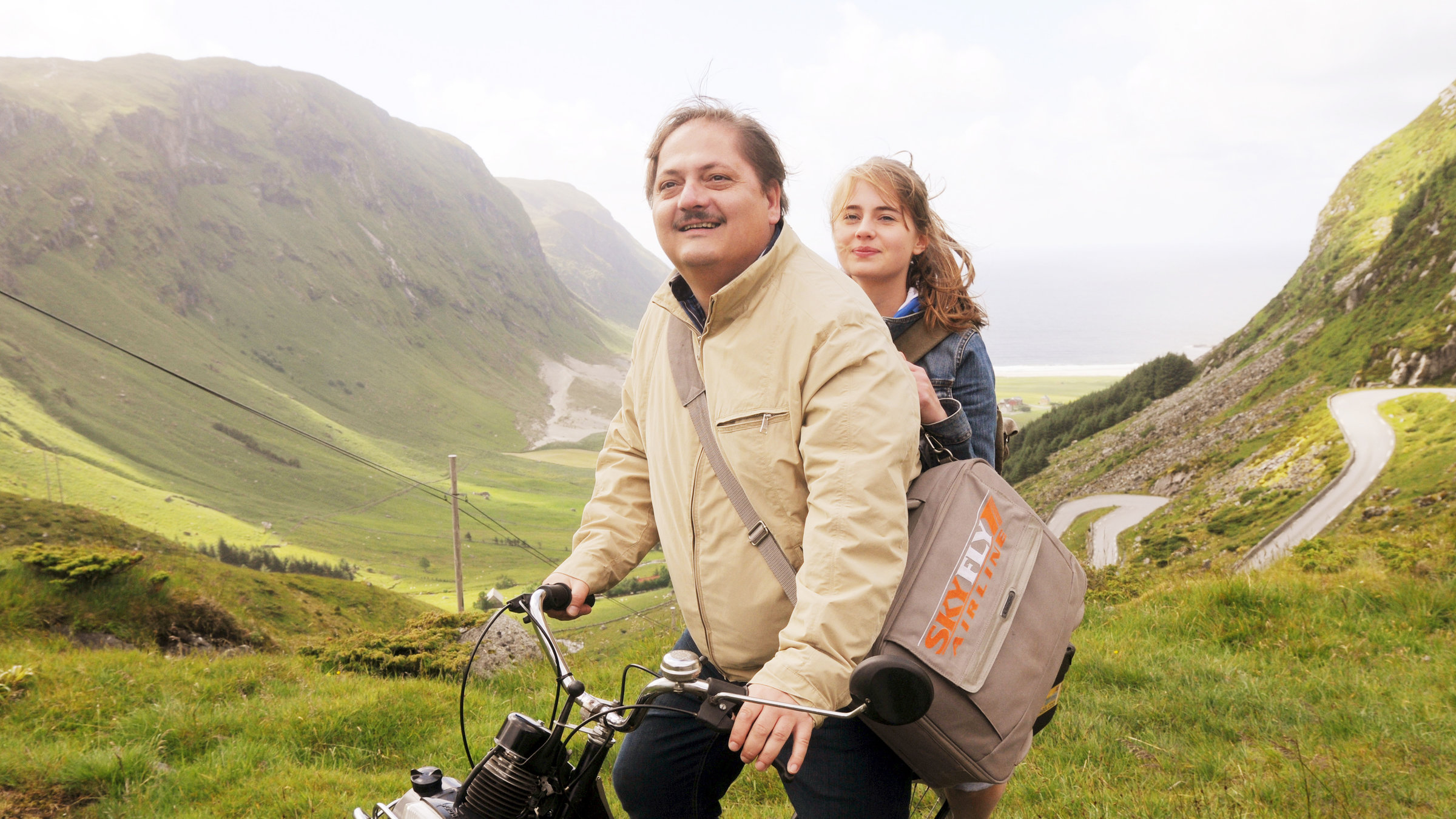 "Ein Mann, ein Fjord": Norbert Krabbe (Jürgen Tarrach) sitzt mit seine Tochter Ute (Olga von Luckwald) auf einem Moped umringt von der norwegischen grünen Fjordlandschaft.