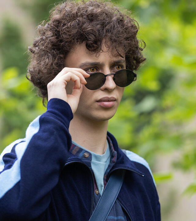 "Club der Dinosaurier - Beast Mode": Im Freien: Ben (Shadi Eck) setzt seine Sonnenbrille ab, wobei seine gelben Augen sichtbar werden.