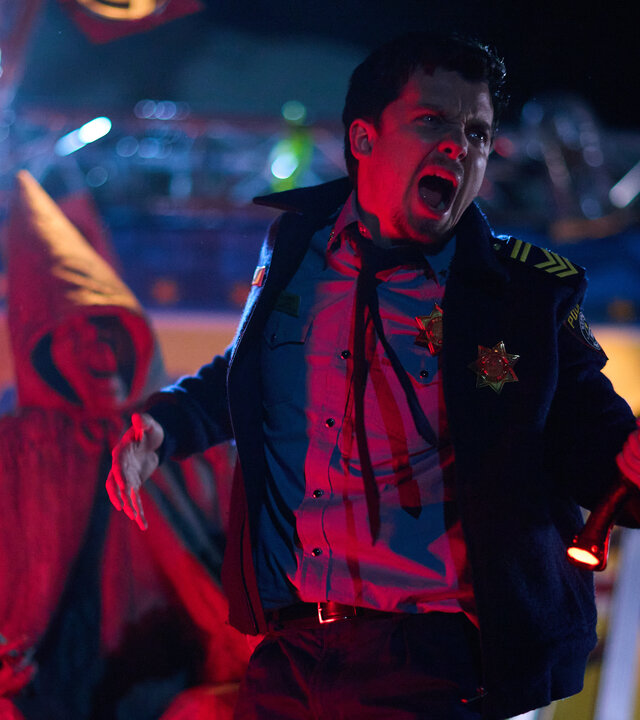 "Gnomes - Angriff der Killerzwerge - Nompton in Aufruhr": Nachts im Freien: Schreiend hebt Kleinstadtpolizist Arnold (Asa Butterfield) eine leuchtende Axt empor. Im Hintergrund steht eine Zwergenfigur und ein Plakat mit der Aufschrift "Welcome".