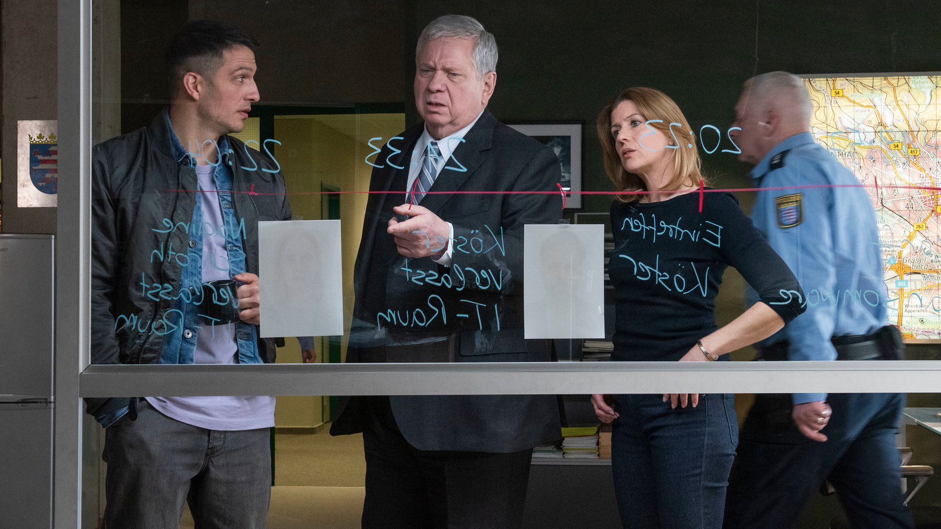 "Der Staatsanwalt - Gestorben wird immer": Max Fischer (Max Hemmersdorfer), Bernd Reuther (Rainer Hunold) und Kerstin Klar (Fiona Coors) stehen hinter einer beschriebenen Glasscheibe. Reuther deutet auf ein Bild.