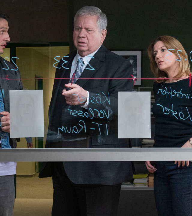 "Der Staatsanwalt - Gestorben wird immer": Max Fischer (Max Hemmersdorfer), Bernd Reuther (Rainer Hunold) und Kerstin Klar (Fiona Coors) stehen hinter einer beschriebenen Glasscheibe. Reuther deutet auf ein Bild.