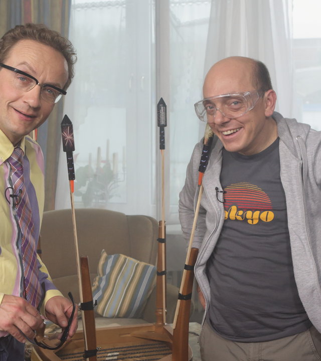 "Nicht nachmachen!": Wigald Boning und Bernhard Hoëcker stehen in einem Wohnzimmer und binden Sylvester-Knaller an Stuhlbeine.