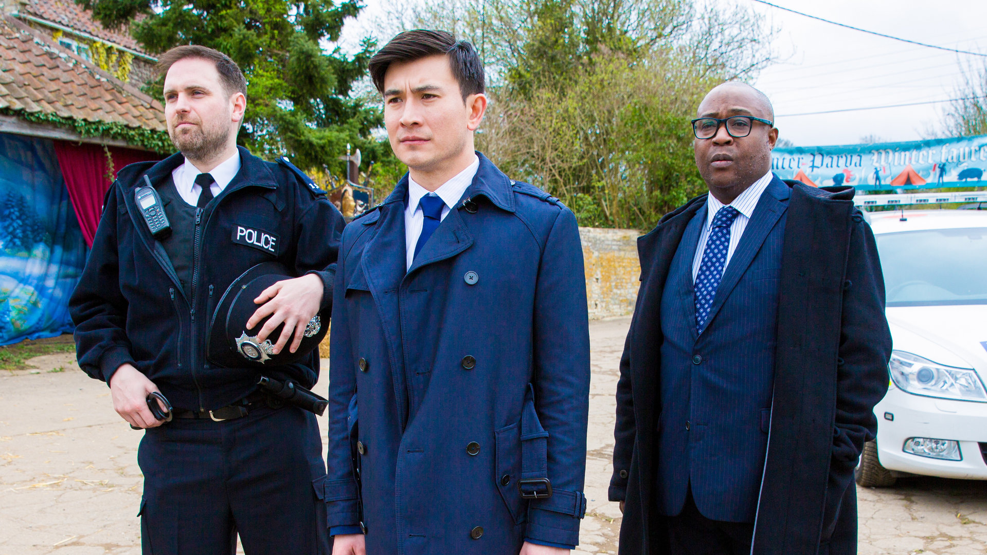 "Agatha Raisin – Und der tote Polizist Teil 2": Die Polizisten Billy Tulloch (Gerry McLaughlin), Bill Wong (Matt McCooey) und DCI Wilkes (Jason Barnett) stehen beim Showdown auf dem Lastwagenparkplatz nebeneinander.
