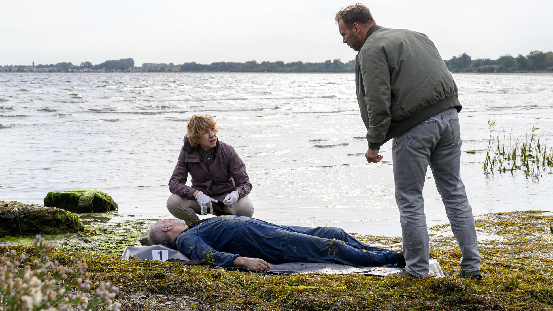 "SOKO Wismar – Tiefe Wasser": Mats Albers (Frank Leal-Soto) liegt tot am Strand. Dr. Helene Sturbeck (Katharina Blaschke), Lars Pöhlmann (Dominic Boeer) und Stefanie Horn (Nicole Ernst) haben sich um ihn versammelt.