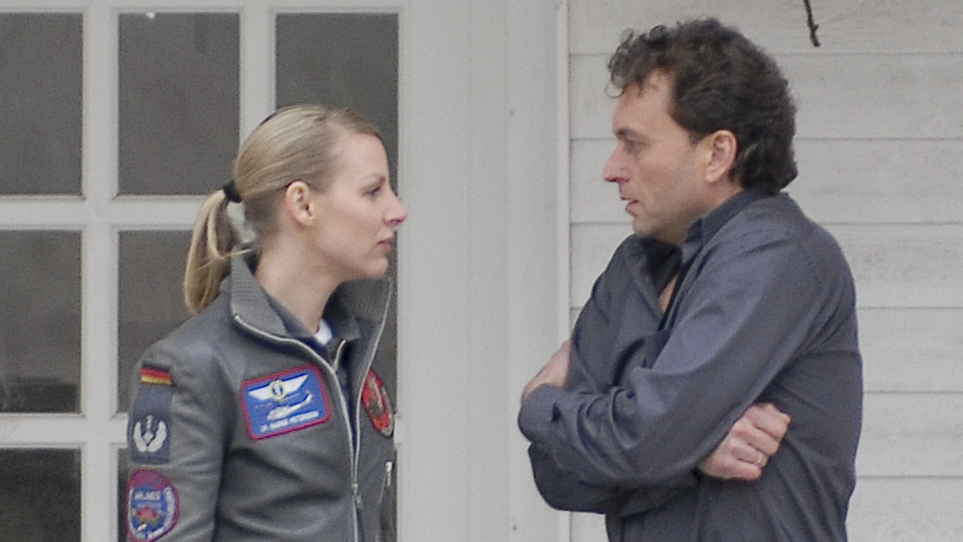 "Die Rettungsflieger - Lust auf Leben": Sabine (Marlene Marlow) steht gemeinsam mit Sebastian Eggers (Thomas Schmuckert), der angespannt die Arme vor der Brust verschränkt hat, auf einer Veranda. Sie blicken sich an.