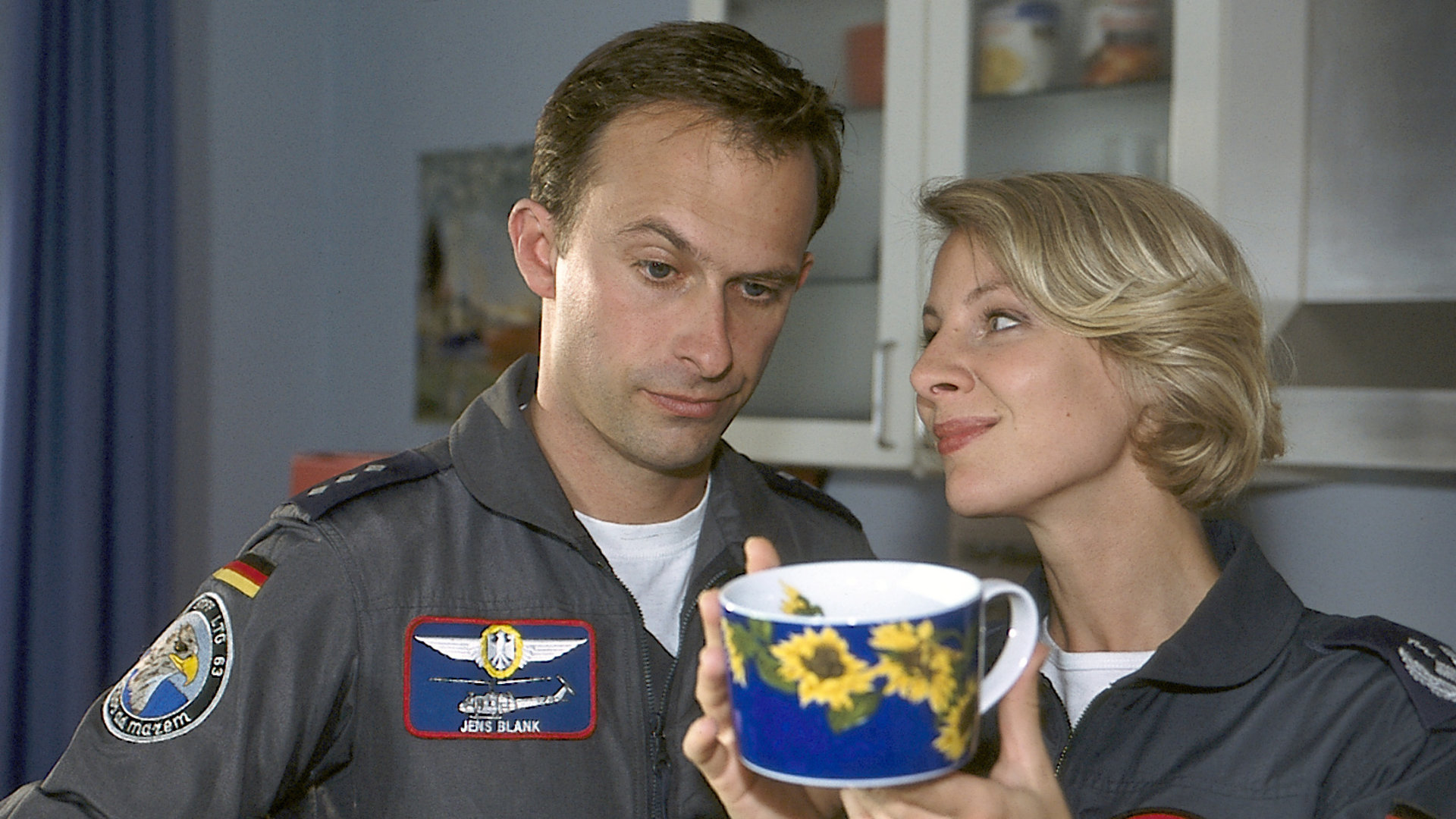 "Die Rettungsflieger - Frischer Wind im Rettungszentrum": Hauptmann Blank (Nicolas König) schaut sich kritisch das neue Kaffeegeschirr an, dass Sabine (Marlene Marlow) in der Hand hält.