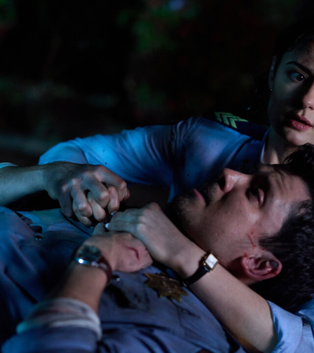 "Gnomes - Angriff der Killerzwerge - Bluttrinker": Arnold (Asa Butterfield) liegt erschöpft in Ellies (Megan Smart) Armen und blickt zu ihr auf. Ellie hält ihn fest umschlungen, während ihr Blick besorgt in die Ferne gerichtet ist.