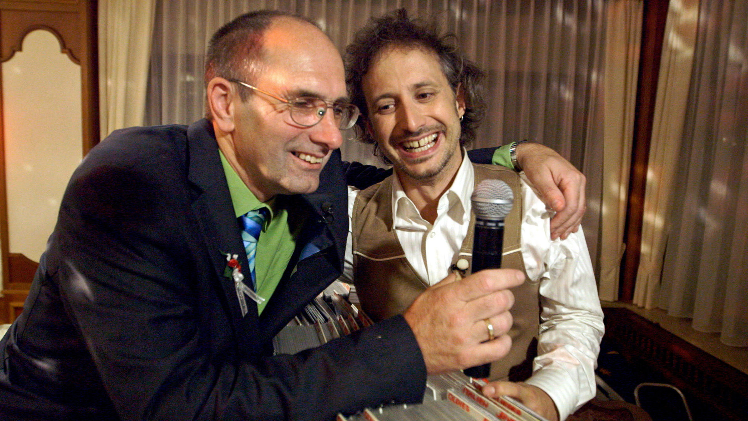 "Herr Ostrowski sucht das Glück - Im Showbusiness": Michael Ostrowski trifft den DJ, Moderator und Alleinunterhalter Peter Rebhahn, der ein Mikrofon in der Hand hält und Michael Ostrowski umarmt.