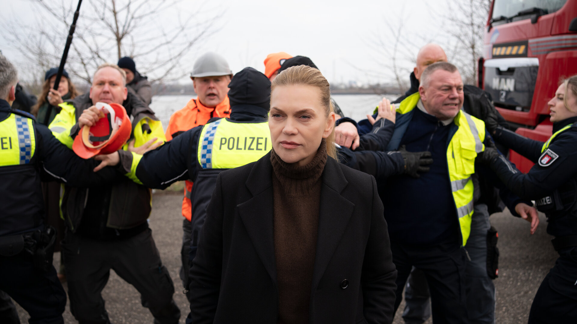"Helen Dorn - Schuld und Sühne": Helen Dorn (Anna Loos) steht draußen. Im Hintergrund halten Polizisten die Demonstranten auf.