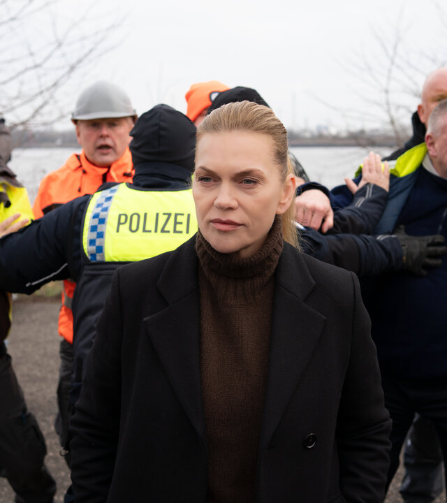 "Helen Dorn - Schuld und Sühne": Helen Dorn (Anna Loos) steht draußen. Im Hintergrund halten Polizisten die Demonstranten auf.