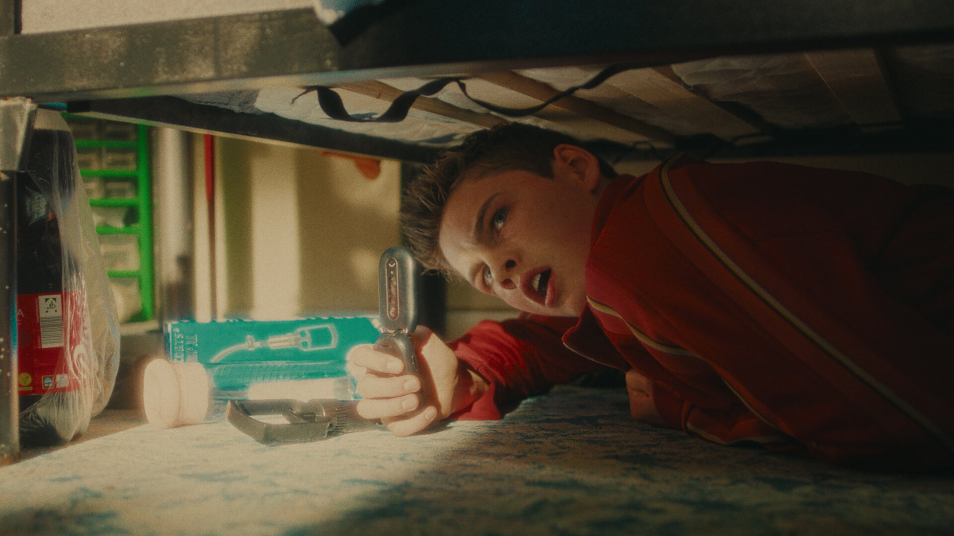 "Chabos - Mmmonster Kill": Peppi (Nico Marischka) liegt unter einem Bett und filmt mit entsetztem Blick etwas mit einem Klapphandy.