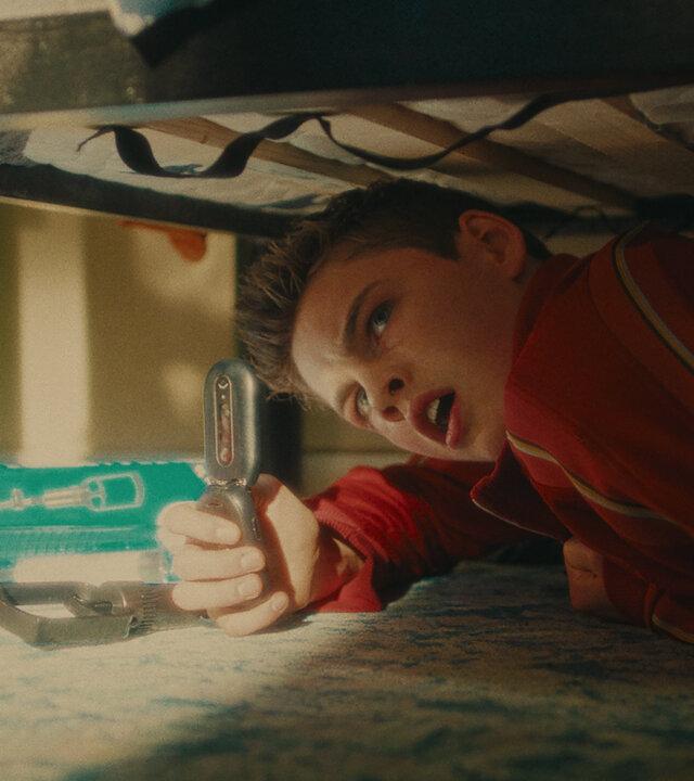 "Chabos - Mmmonster Kill": Peppi (Nico Marischka) liegt unter einem Bett und filmt mit entsetztem Blick etwas mit einem Klapphandy.