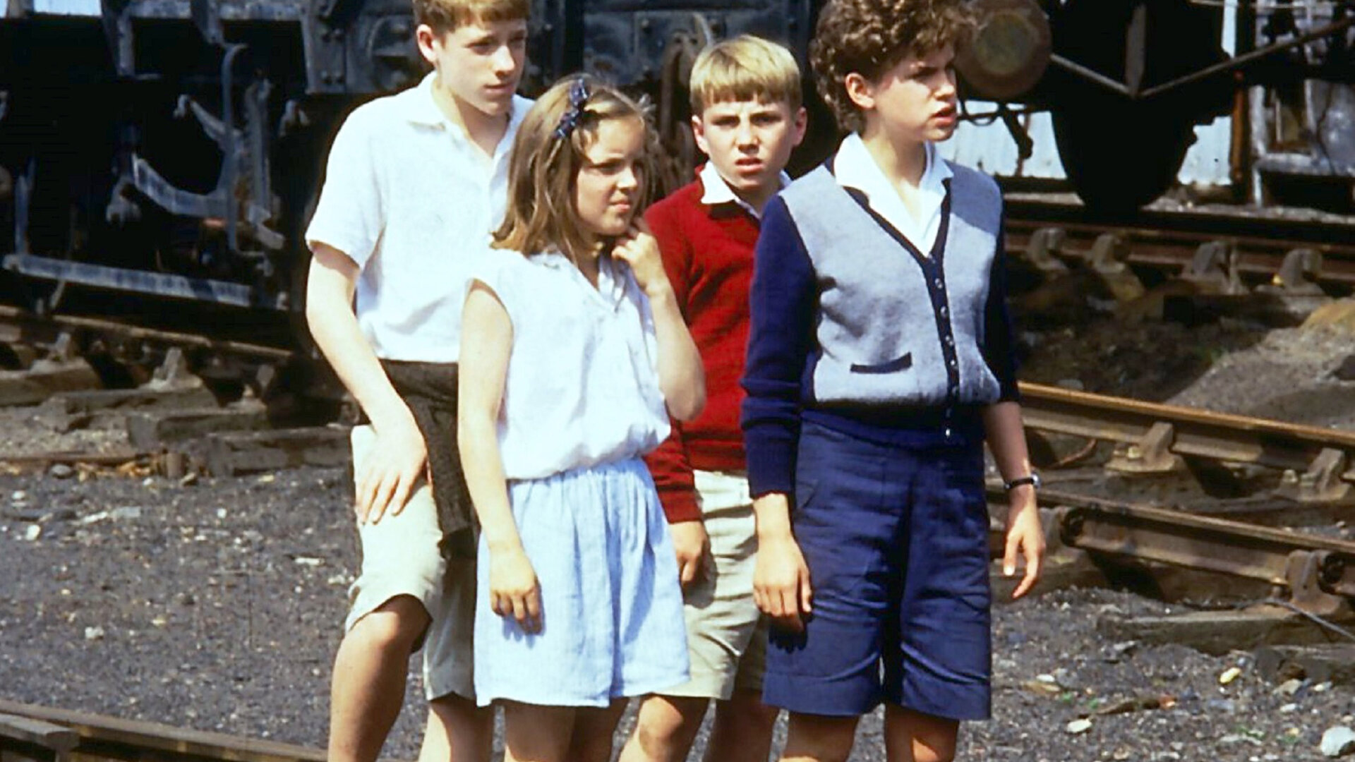 "Fünf Freunde im Zeltlager": Julian (Marco Williamson), Anne (Laura Petela), Dick (Paul Child) und George (Jemima Rooper) stehen auf den Zugschienen vor einem stehenden Zug und blicken aufmerksam um sich.