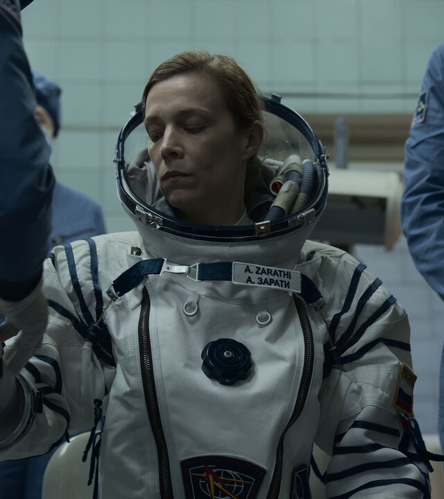 "Infiniti - Also sprach Zarathustra": Anna (Céline Sallette) sitzt angespannt inmitten mehrerer Personen mit Schutzanzügen, während ihr ein Raumanzug angelegt wird.