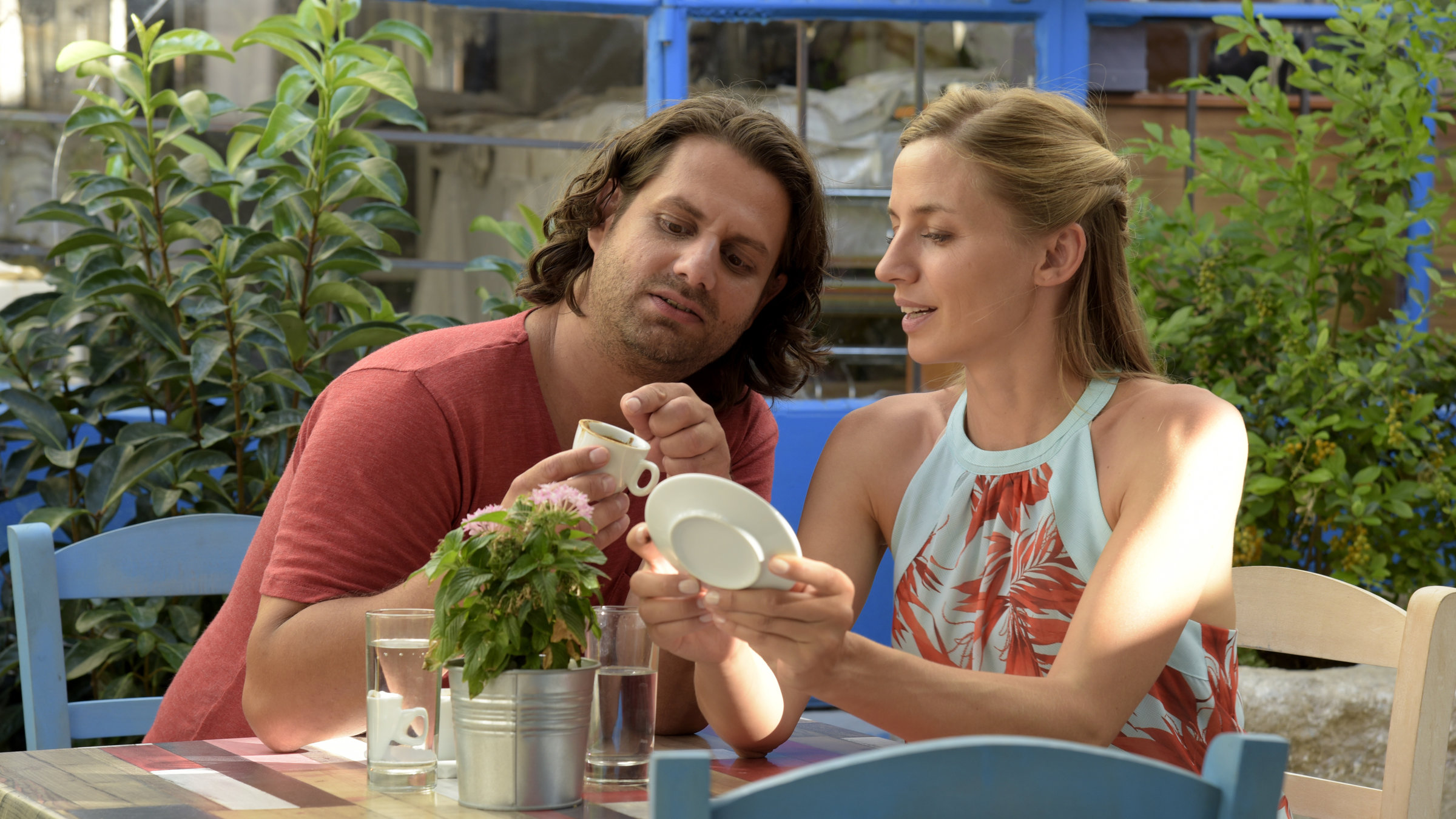 "Ein Sommer auf Zypern": In einem Kaffee sitzen Elyas Basdekis (Adam Bousdoukos) und Tina Driesen (Annika Blendl) an einem Tisch und lesen im Kaffeesatz.