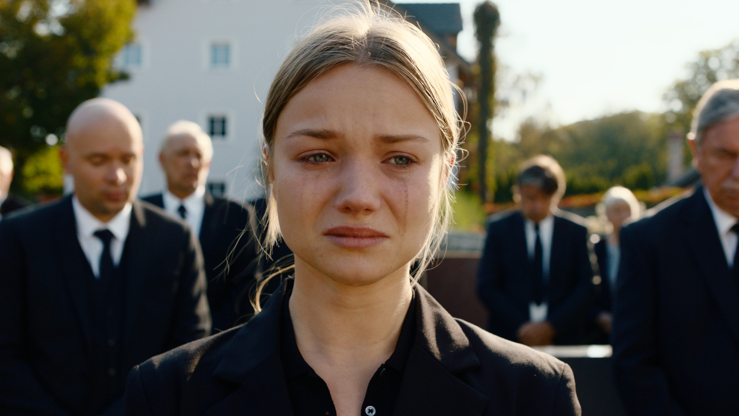 "Gestern waren wir noch Kinder (3)": Nahaufnahme. Vivi Klettmann (Julia Beautx) trägt schwarz und weint, ihr Make-up ist verlaufen. Im Hintergrund sind weitere Trauergäste verschwommen zu sehen.