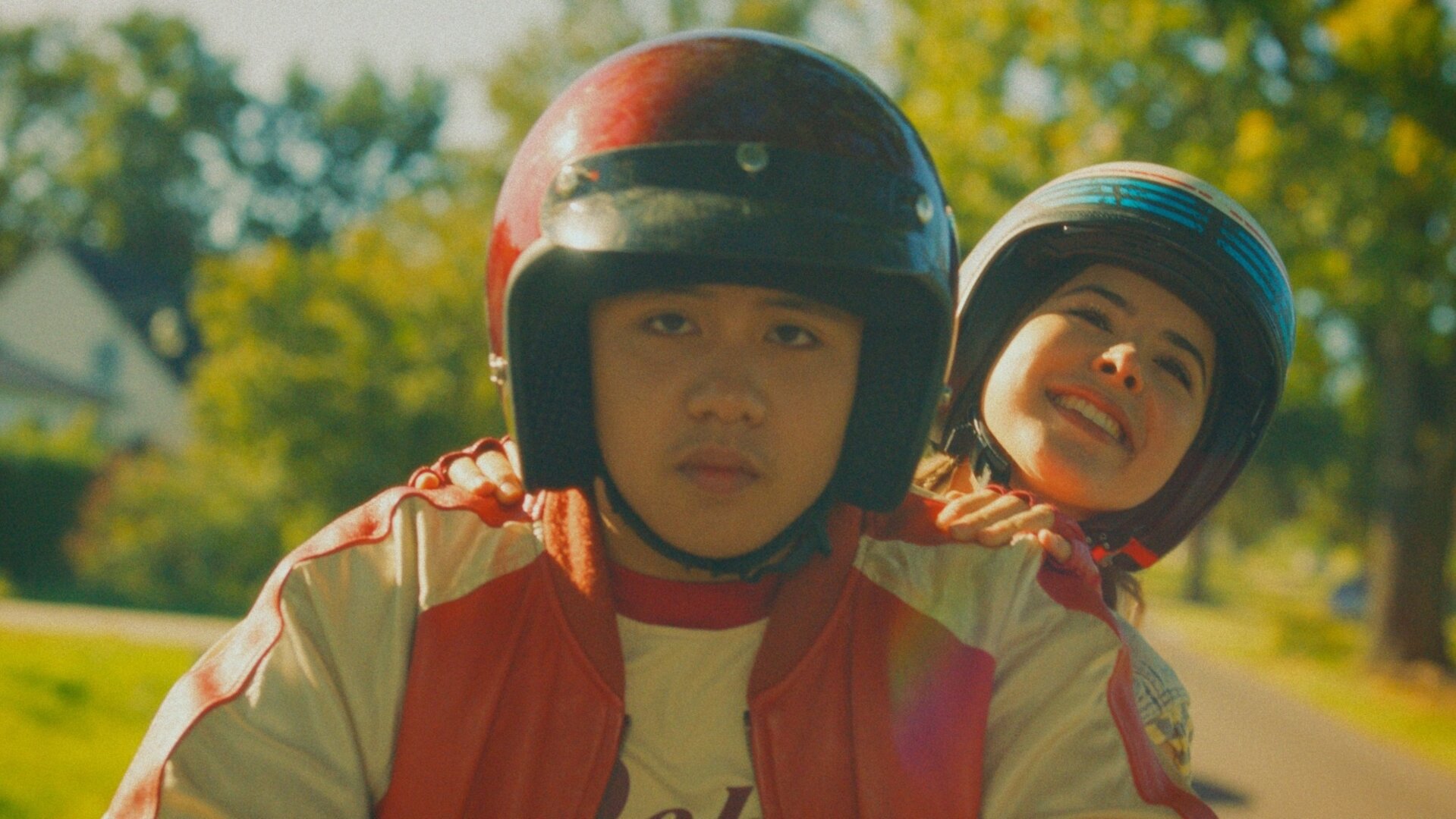 "Doppelhaushälfte – Roadtrip": Rocco Knuppe (Hoang Minh Ha) fährt auf einem Motorroller, Zoe Sawadi (Helena Yousefi) sitzt lachend hinter ihm und hält sich fest. Beide tragen Helme.