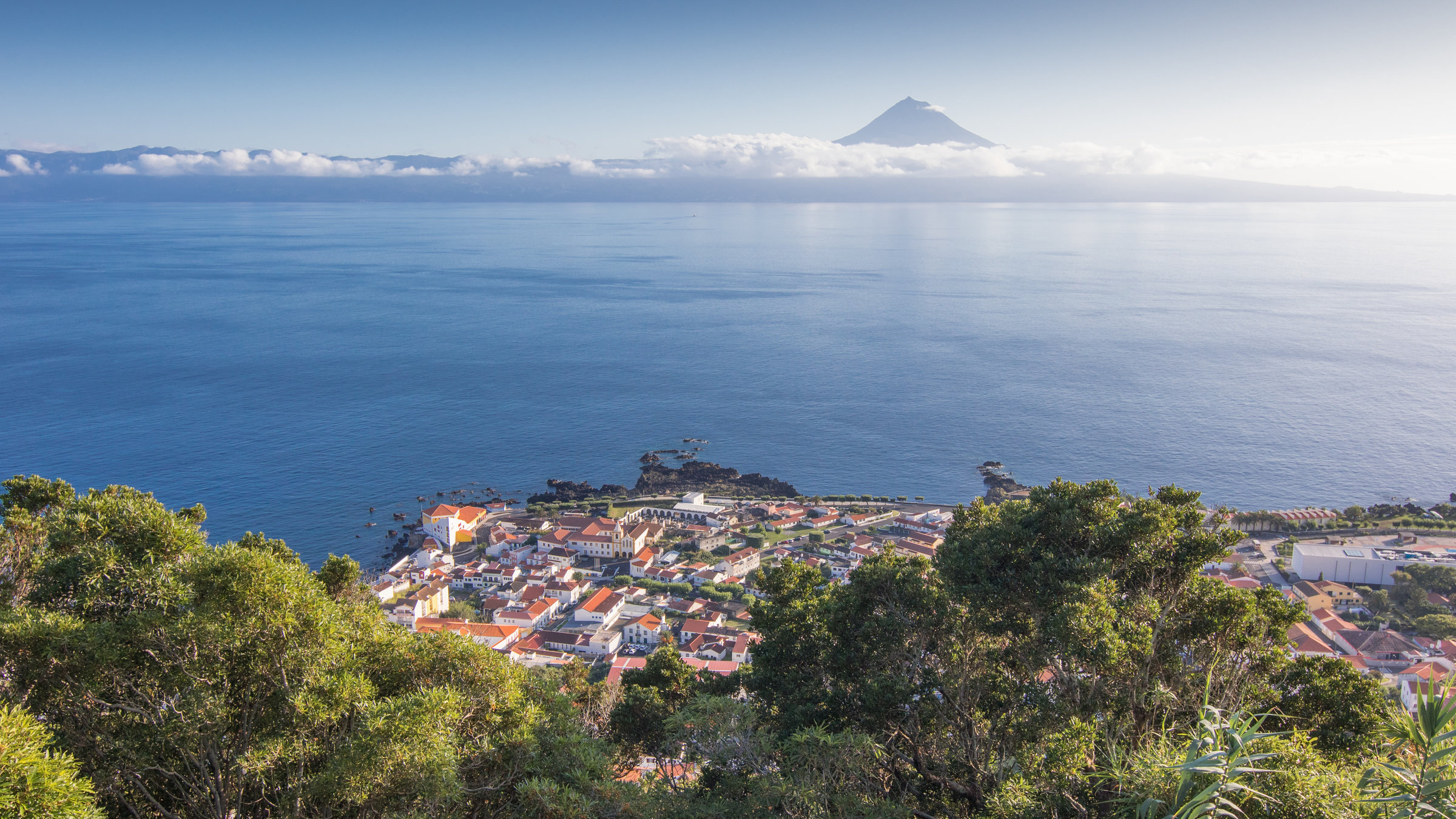"Traumorte - Azoren": Grüne Landschaft und Blick über das Meer auf eine Vulkanspitze.