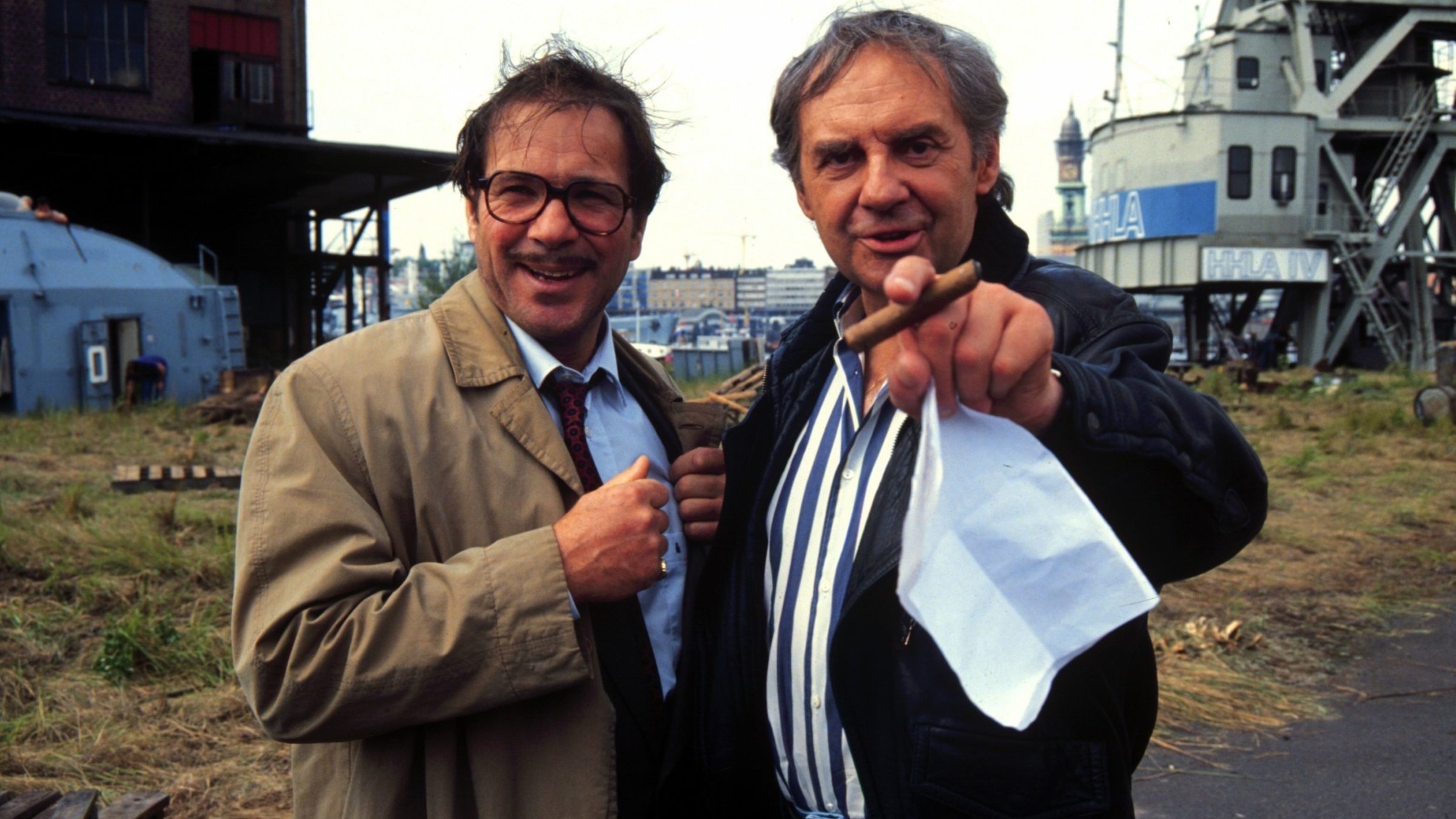 "ZDF-History: Deutsche Leinwandhelden": Götz George und Harald Juhnke stehen nebeneinander vor einer Industriekulisse und lachen in die Kamera.