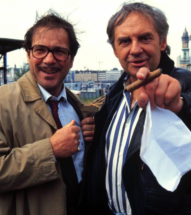 "ZDF-History: Deutsche Leinwandhelden": Götz George und Harald Juhnke stehen nebeneinander vor einer Industriekulisse und lachen in die Kamera.