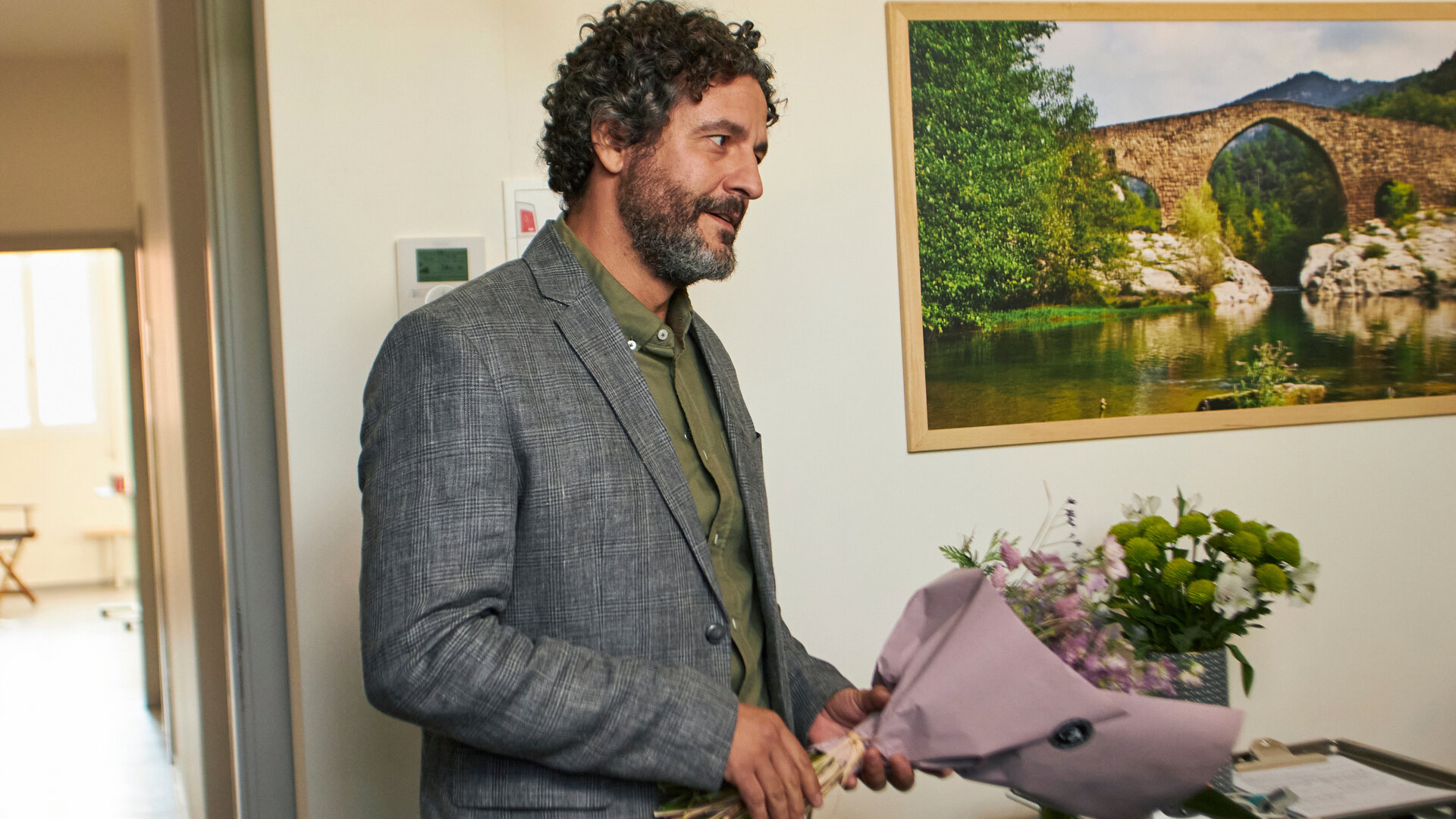 "The Diplomat - Die Hochzeit": Inspector Castells (Isak Férriz) steht mit einem Blumenstrauß in der Hand im Krankenzimmer.