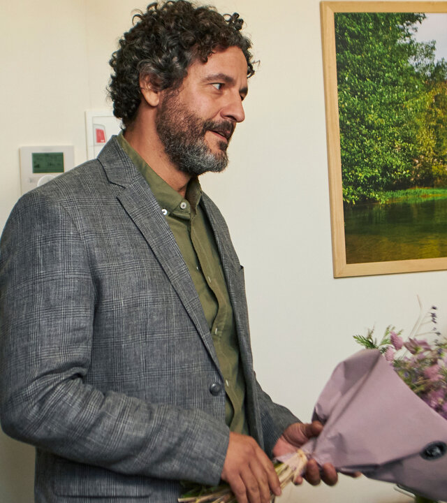 "The Diplomat - Die Hochzeit": Inspector Castells (Isak Férriz) steht mit einem Blumenstrauß in der Hand im Krankenzimmer.
