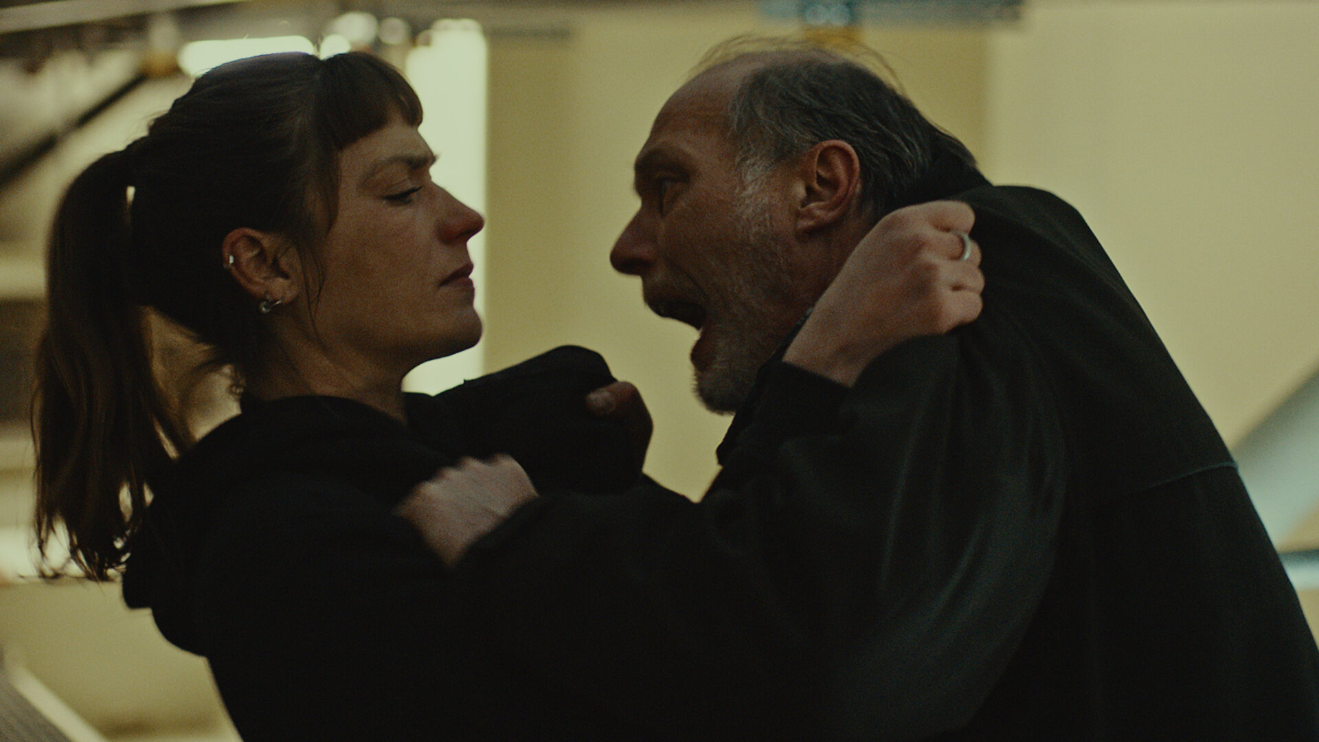 „STRALSUND – Jetzt komm ich!“: Im klaustrophobischen Inneren der Stralsund-Brücke greift Detlev Schulte (Martin Brambach, re) Jule Zabek (Sophie Pfennigstorf, li) an, in dem er sie brutal am Kragen packt. Wir sehen beide nah.