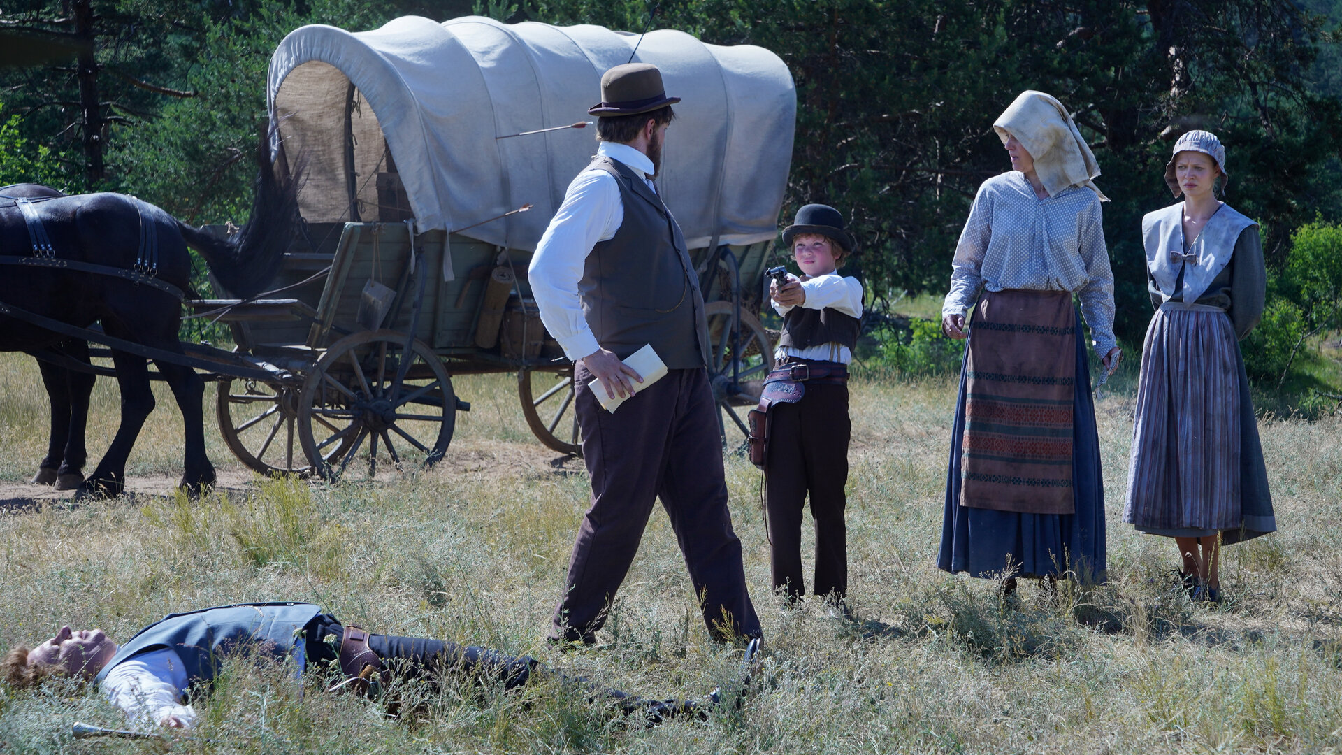 "Sketch History - Wilder Westen, Wilder Osten": Der Makler (Paul Sedlmeir) liegt erschossen im Gras. Im Hintergrund steht ein Planwagen mit zwei Rappen. Neben dem Makler stehen Vater Walter (Jan van Weyde), Mutter Dolores (Judith Richter), Tochter Paula (Nora Islei) und Sohn Fritz (Komparse). Fritz hat eine Pistole in den Händen und zielt.