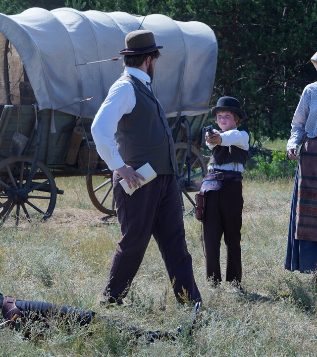 "Sketch History - Wilder Westen, Wilder Osten": Der Makler (Paul Sedlmeir) liegt erschossen im Gras. Im Hintergrund steht ein Planwagen mit zwei Rappen. Neben dem Makler stehen Vater Walter (Jan van Weyde), Mutter Dolores (Judith Richter), Tochter Paula (Nora Islei) und Sohn Fritz (Komparse). Fritz hat eine Pistole in den Händen und zielt.
