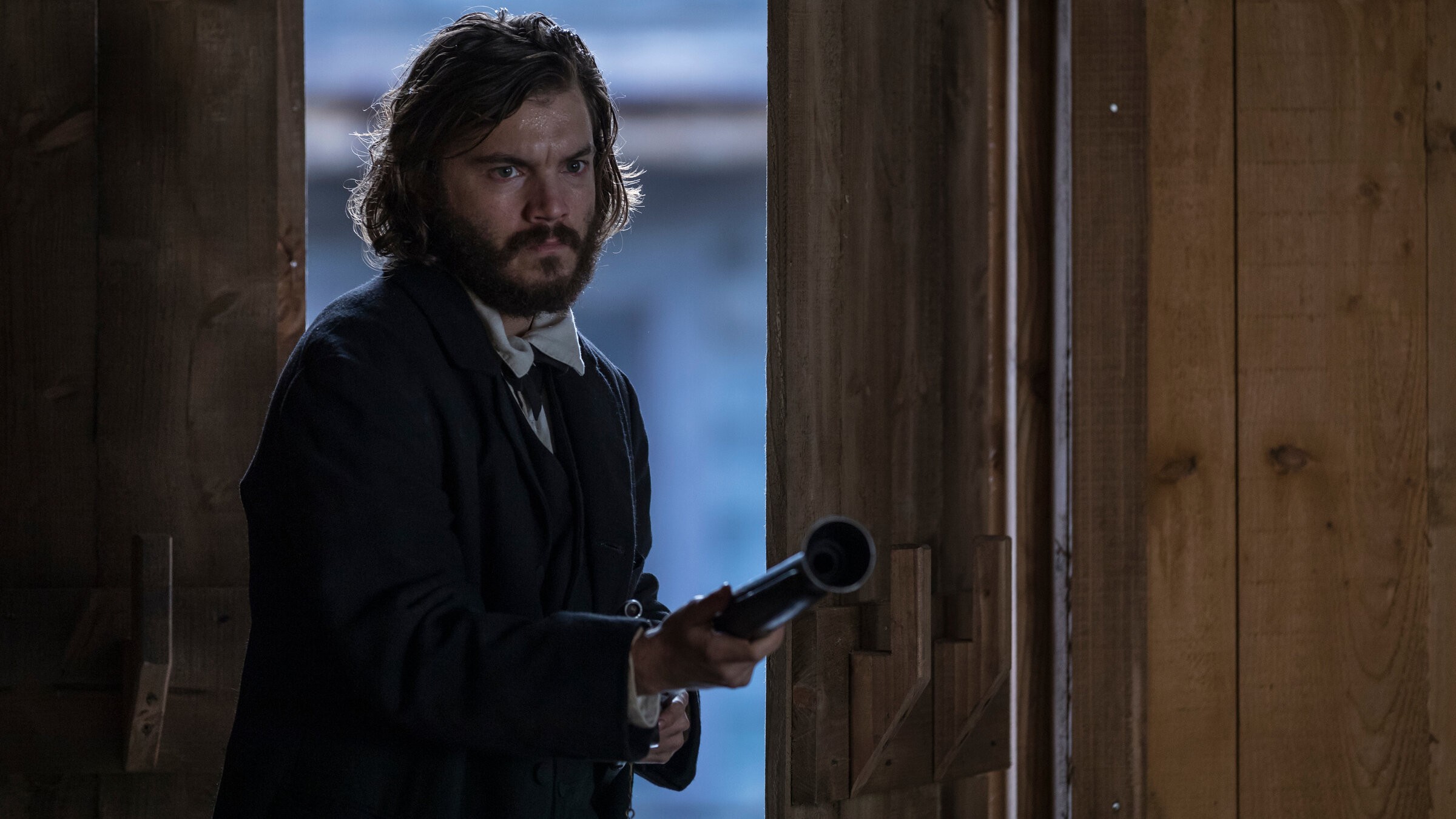 „Never Grow Old“: Patrick Tate (Emile Hirsch) betritt mit entschlossenem Gesichtsausdruck und einem Gewehr in Anschlag ein Gebäude.