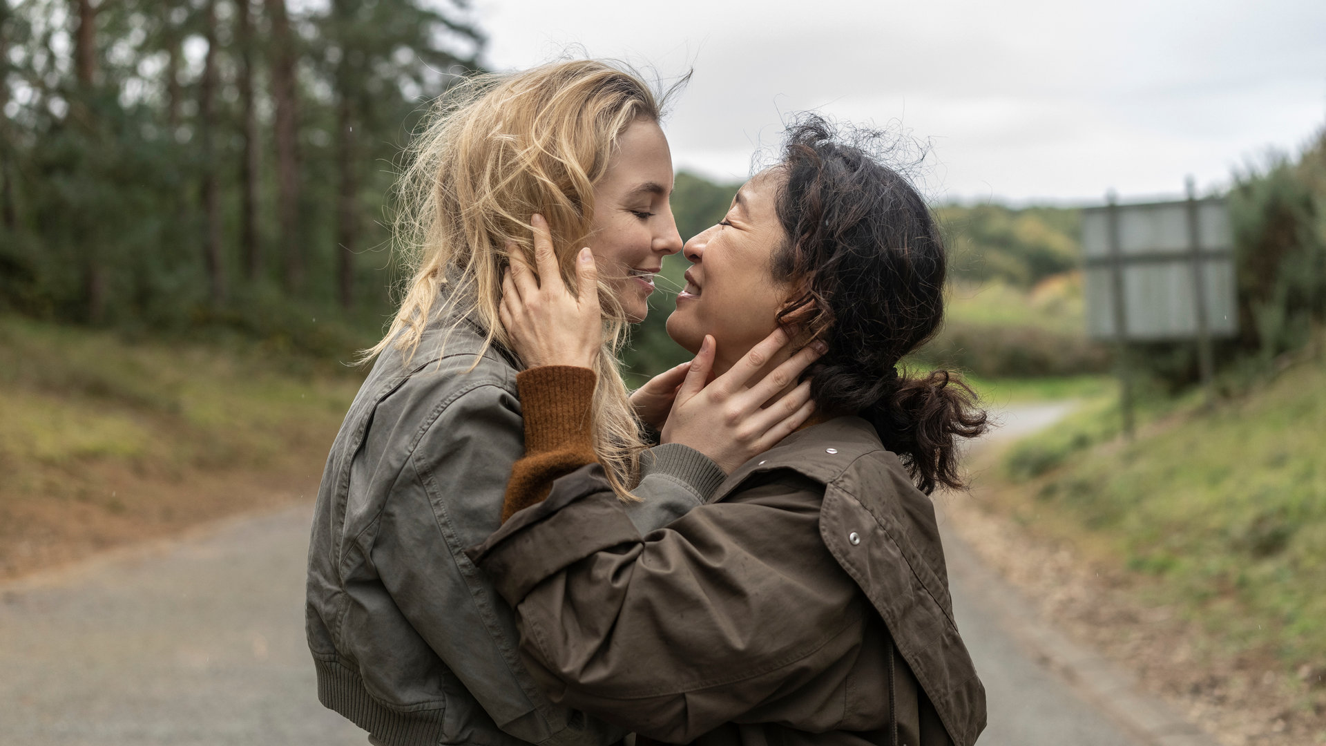"Killing Eve - Hallo, ihr Verlierer": Eve (Sandra Oh) und Villanelle (Jodie Comer) halten sich auf einer Landstraße eng in den Armen und lächeln sich gegenseitig an.