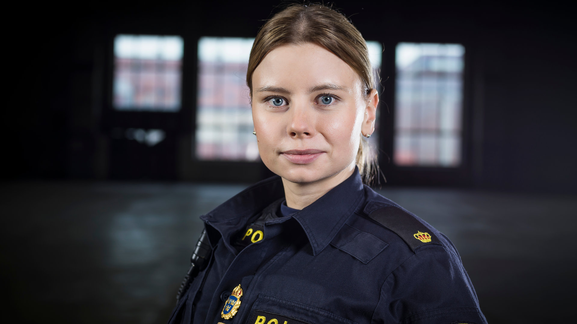 "Thin Blue Line - Ankunft": Sara (Amanda Jansson) steht in einem dunklem Raum und schaut konzentriert in Richtung Kamera.