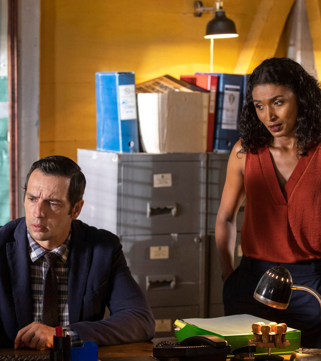 "Death in Paradise - Die Gabe des Teufels II": Camille Bordey (Sara Martins) und Commissioner Patterson (Don Warrington) stehen neben DI Parker (Ralf Little) in einem Büro und schauen mit ihm auf einen Monitor.
