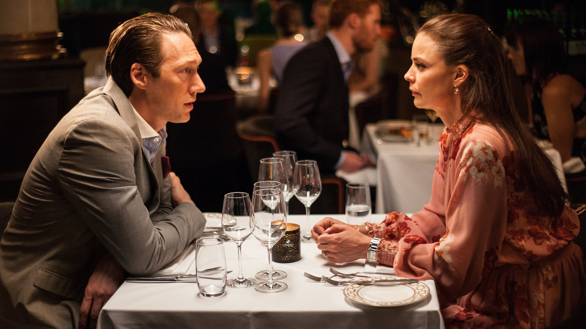 "Exit - Lügen": Adam Veile (Simon J. Berger) und Hermine Veile (Agnes Kittelsen) sitzen sich am gedeckten Tisch in einem Restaurant gegenüber. Beide blicken sich ernst an.