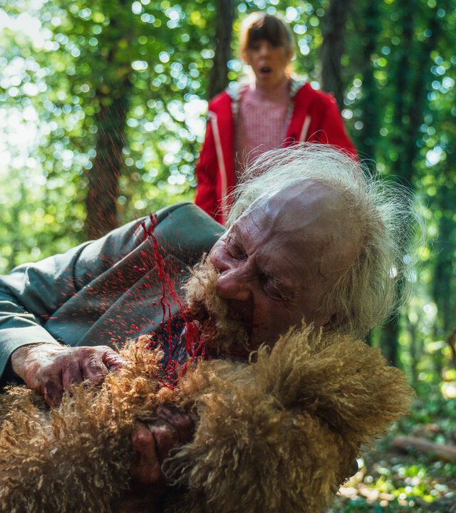 "Generation Z - Ausbruch": Frank (Paul Bentall) hält im Wald einen Hund umklammert und beißt ihn. Im Hintergrund beobachtet Jane (Rebecca Humphries) die Szene mit offenem Mund und weit aufgerissenen Augen.