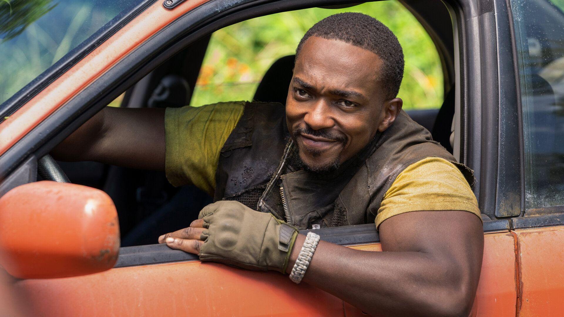 "Twisted Metal - WLUDRV": John Doe (Anthony Mackie) sitzt am Steuer eines orangefarbenen Wagens und lehnt sich lächelnd aus dem offenen Fenster.