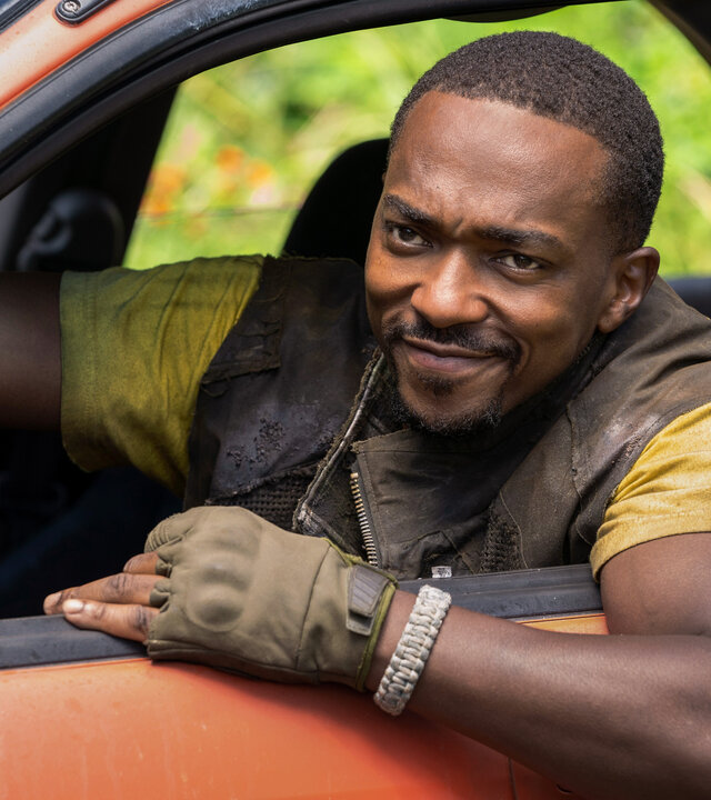 "Twisted Metal - WLUDRV": John Doe (Anthony Mackie) sitzt am Steuer eines orangefarbenen Wagens und lehnt sich lächelnd aus dem offenen Fenster.