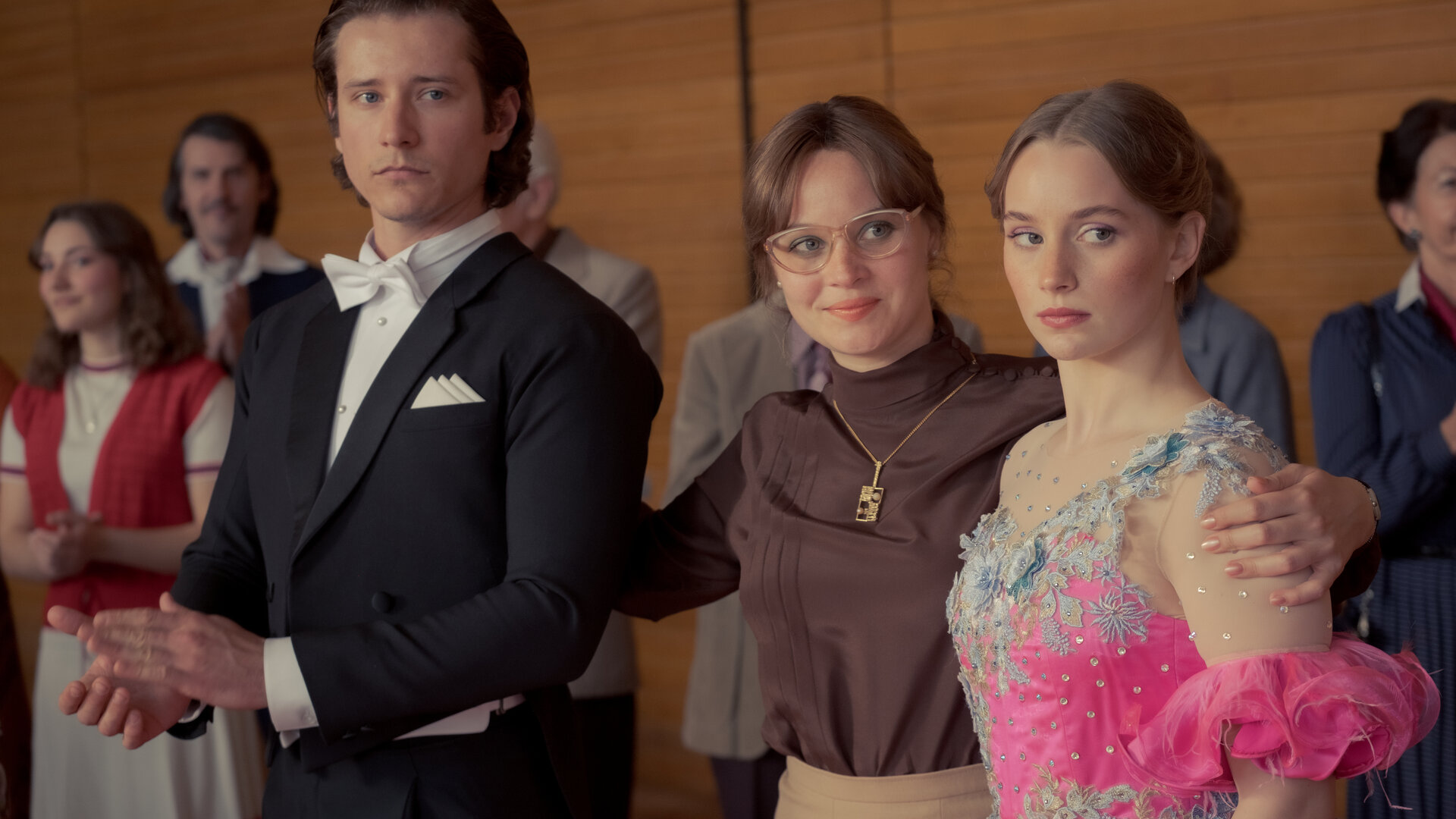 "Ku'damm 77": Steffen Henke (Benedikt Kalcher), Monika Franck-Schöllack (Sonja Gerhardt) und Dorli Schöllack (Carlotta Bähre) stehen nebeneinander in einer Sporthalle und blicken nach vorne.