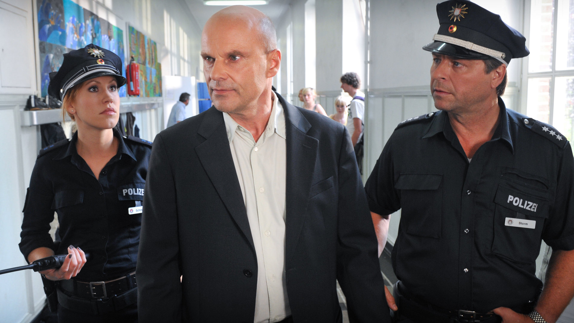 "Notruf Hafenkante - Risiken und Nebenwirkungen": Jule (Wolke Hegenbarth), Direktor Wiesenrath (Alexander Radszun) und Henning (Uwe Fellensiek) stehen auf einem Schulflur. Wiesenrath und Henning schauen in die gleiche Richtung, während Jule den Direktor ansieht.