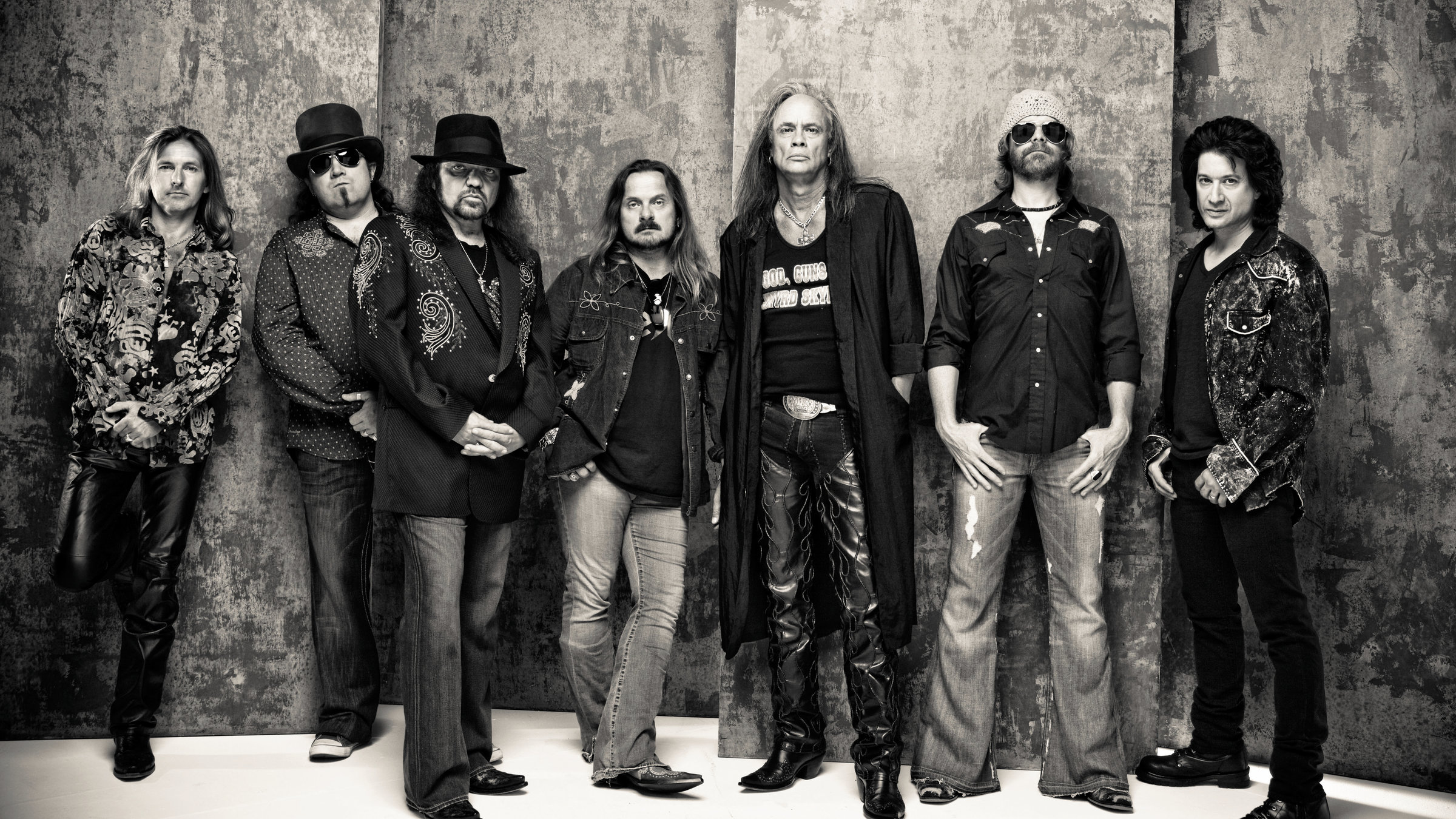 "Lynyrd Skynyrd: Live at the Ryman - Celebrating 50 Years": s/w Foto der Band Lynyrd Skynyrd. Die Bandmitglieder stehen nebeneinander vor einer Wand und blicken in die Kamera.