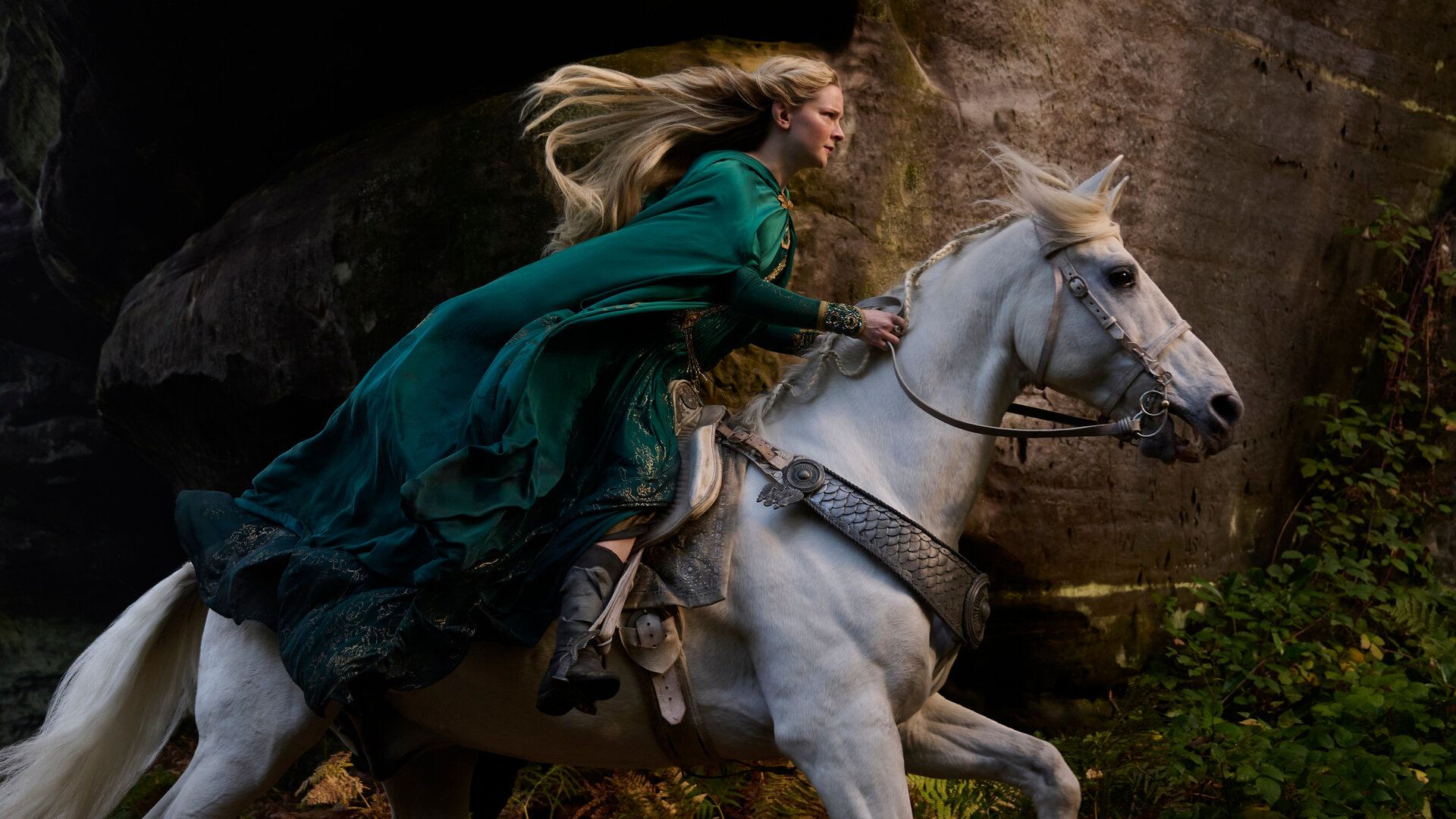 "Der Herr der Ringe: Die Ringe der Macht - Elbenkönige hoch im Licht": Galadriel (Morfydd Clark) reitet auf einem weißen Pferd durch einen Wald. Ihr langes Haar weht nach hinten.