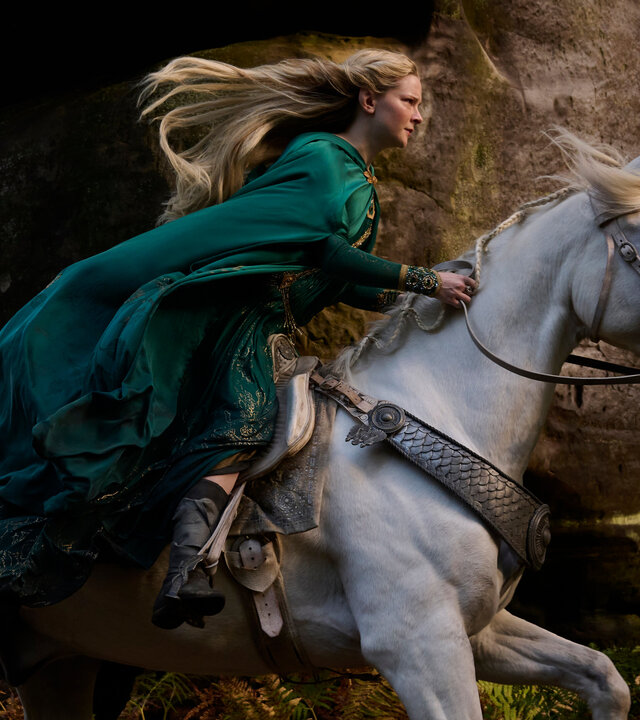 "Der Herr der Ringe: Die Ringe der Macht - Elbenkönige hoch im Licht": Galadriel (Morfydd Clark) reitet auf einem weißen Pferd durch einen Wald. Ihr langes Haar weht nach hinten.