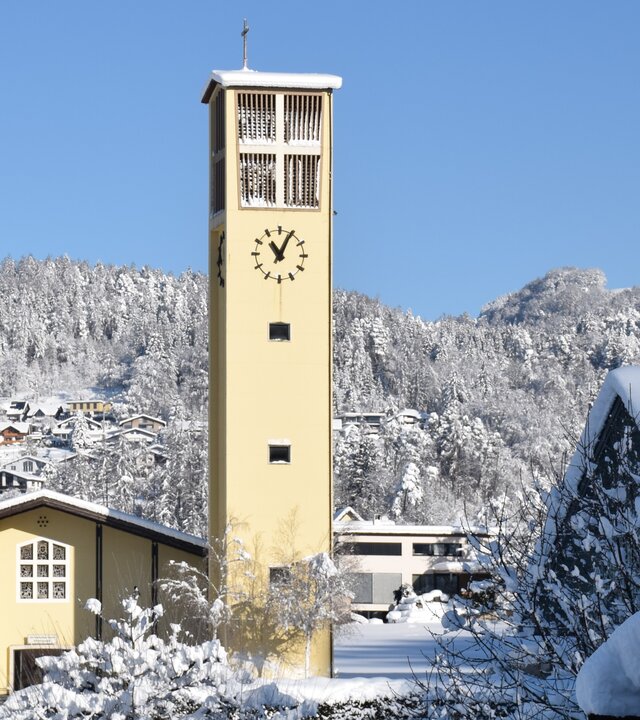 "Katholischer Gottesdienst - Was bleibt von Weihnachten?": Außenansicht der Pfarrkirche in Muntlix, Vorarlberg, in verschneiter Umgebung mit strahlend blauem Himmel.